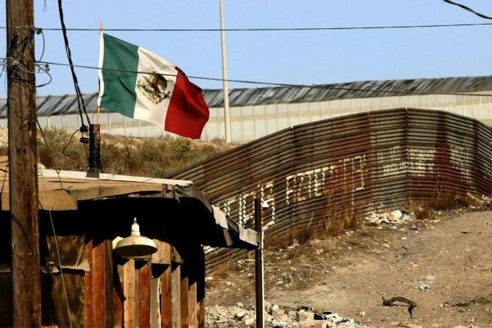 A Mexican flag flies next to the wall which separates Mexico from the United States in Tijuana