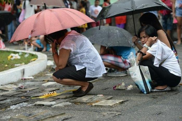 People offer prayers and light candles in front of graves of dead relatives during the annual All Saints' Day tradition in Manila on November 1, 2016