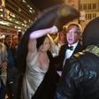 A woman throws her fur coat over her head outside the National Press Club in Washington, DC on January 19, 2017 as protesters shouted at them as they left the "Deploraball" event in honour of new US president Donald Trump