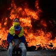 A Venezuelan opposition activist is backdropped by a burning barricade during a demonstration against President Nicolas Maduro in Caracas, on April 24, 2017