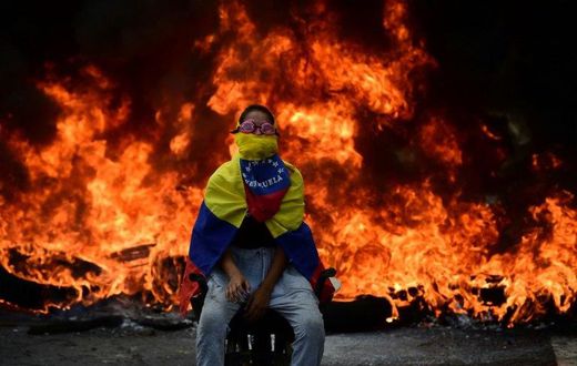 A Venezuelan opposition activist is backdropped by a burning barricade during a demonstration against President Nicolas Maduro in Caracas, on April 24, 2017