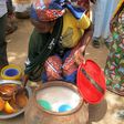 A photo taken on February 23, 2017 shows a woman selling bil-bil, a homemade brew made from millet, sorghum or corn, in Mazogo, in the extreme north of Cameroon