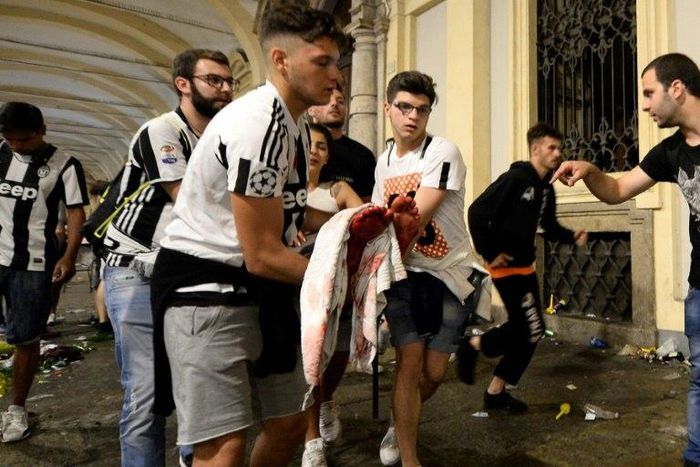 Juventus supporters carry an injured woman in Piazza San Carlo in Turin after a stampede in the fanzone where fans were watching the Champions League Final between Juventus and Real Madrid on a giant screen, on June 3, 2017