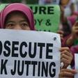 An Indonesian migrant worker holds up a placard during a vigil for slain colleagues Seneng Mujiasih and Sumarti Ningsih in Hong Kong