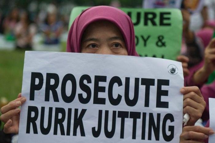 An Indonesian migrant worker holds up a placard during a vigil for slain colleagues Seneng Mujiasih and Sumarti Ningsih in Hong Kong