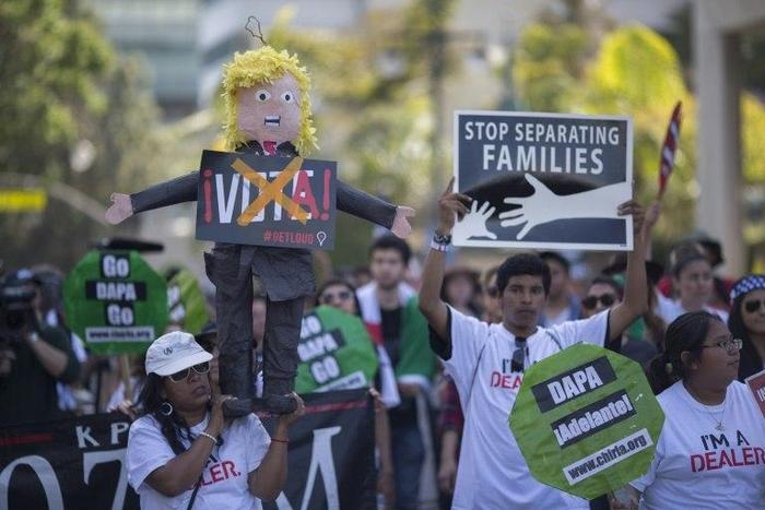 A woman carries a pinata based on Donald Trump during one of several May Day marches in Los Angeles, California