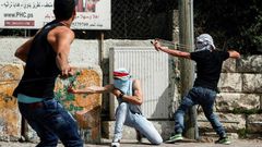 Palestinian protesters use slingshots to hurl stones towards Israeli security forces during clashes in the West Bank town of Bethlehem on April 21, 2017, in solidarity with the hunger striking prisoners
