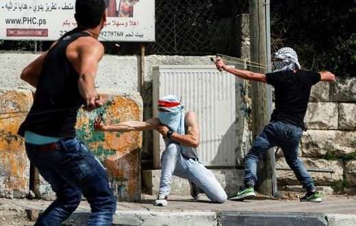 Palestinian protesters use slingshots to hurl stones towards Israeli security forces during clashes in the West Bank town of Bethlehem on April 21, 2017, in solidarity with the hunger striking prisoners