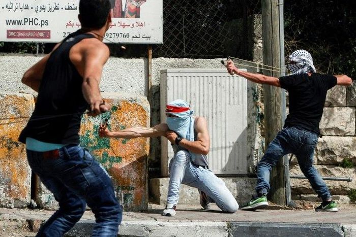Palestinian protesters use slingshots to hurl stones towards Israeli security forces during clashes in the West Bank town of Bethlehem on April 21, 2017, in solidarity with the hunger striking prisoners