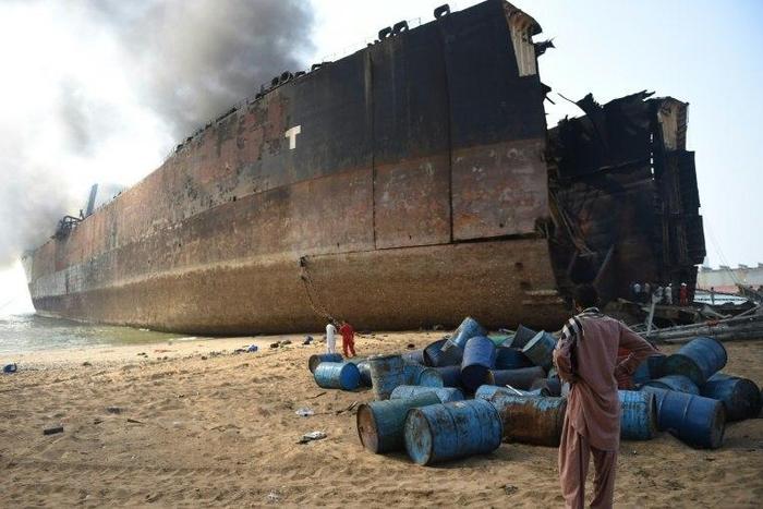 A Pakistani man looks at the wreckage of a burning ship a day after a gas cylinder explosion at the Gadani shipbreaking yard