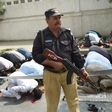 A Pakistani policeman stands guard as Muslims offer Friday prayers on a street in Karachi, on February 17, 2017