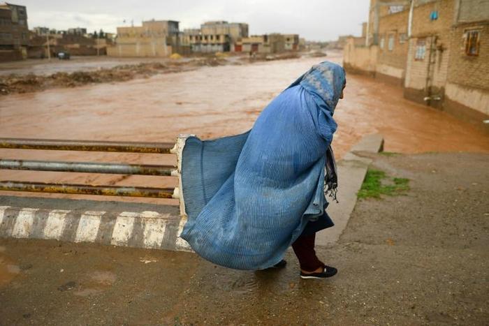 A burqa-clad Afghan woman crosses a bridge following flash floods in Herat province