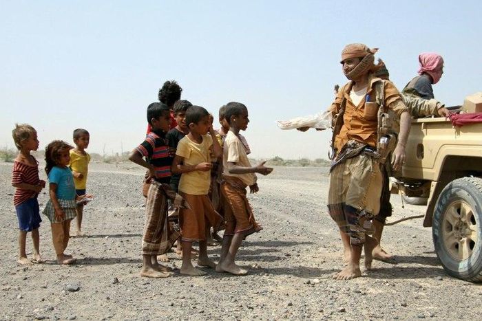 Pro-regime fighters give food to Yemeni children on the road leading to the southwestern port city of Mokha, on January 26, 2017