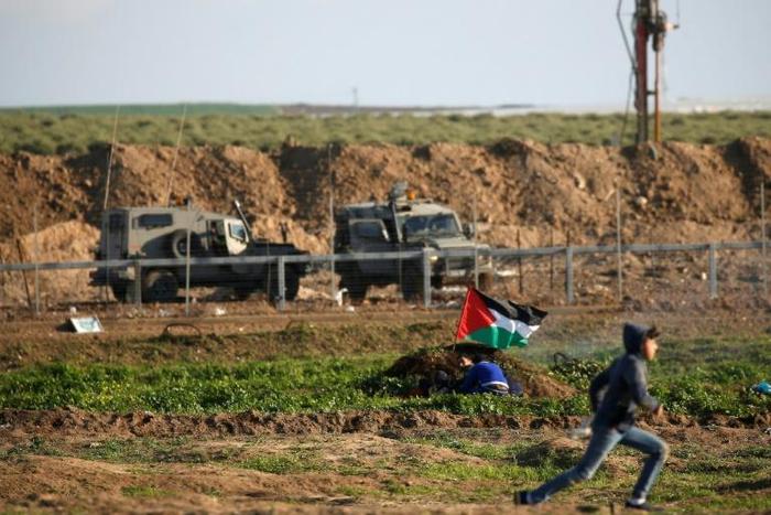 Palestinian protesters take cover during a demonstration along the demarcation line with Israel, east of Gaza City, on January 18, 2019
