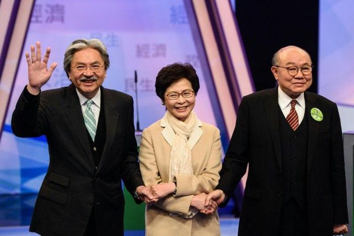 Hong Kong's three leadership candidates (L-R) John Tsang, Carrie Lam and ex-judge Woo Kwok-hing join hands in a Hong Kong TV studio before facing off in their first televised debate on March 14, 2017