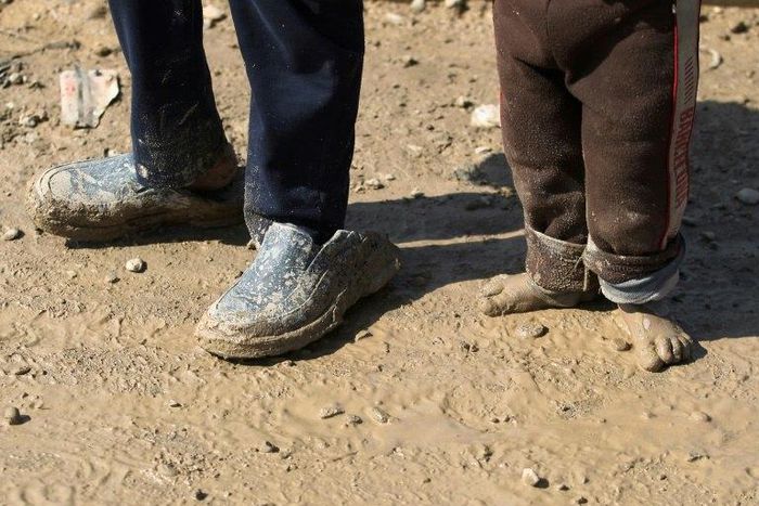 Displaced Iraqi children from Mosul walk in the mud towards refugee camps on March 24, 2017