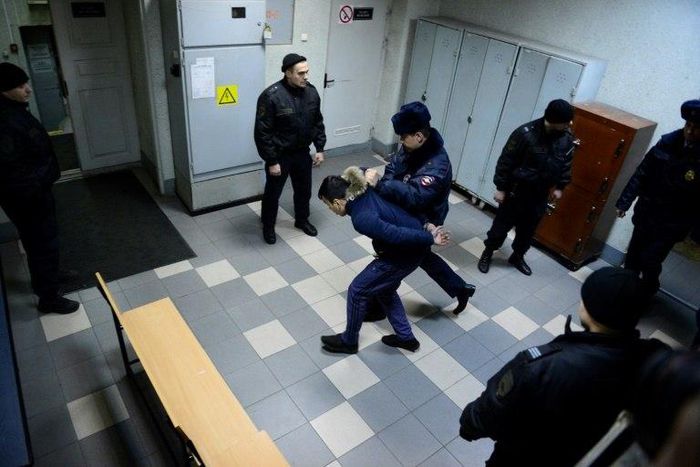 A police officer escorts a man suspected of involvement in the Saint Petersburg metro bombing inside a court building in Saint Petersburg on April 7, 2017