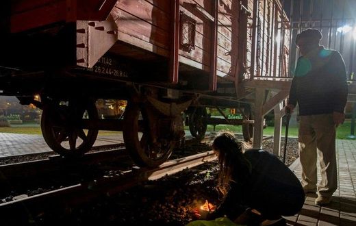 Chen and her grandfather Avraham, 85, a Holocaust survivor, light candles next to a train wagon used to transport Jews to concentration camps, in Netanya on April 23, 2017