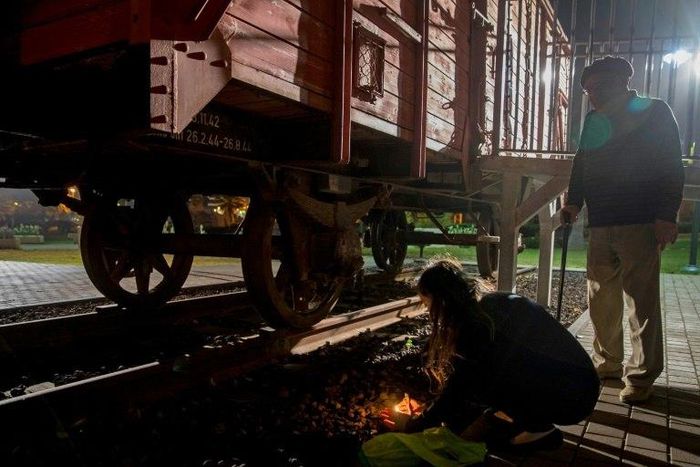 Chen and her grandfather Avraham, 85, a Holocaust survivor, light candles next to a train wagon used to transport Jews to concentration camps, in Netanya on April 23, 2017
