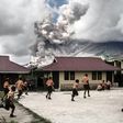 Children play at school as Indonesia's Mount Sinabung spews clouds of smoke and ash on February 10, 2017