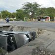 A car damaged by a bus lies on the side of a road in Gonaives