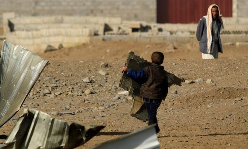 A child carries corrugated metal from the site of a reported airstrike by the Saudi-led coalition in the Yemeni capital Sanaa in January