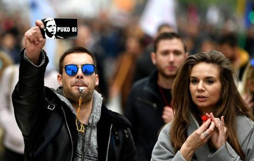 A protestor holds a sticker showing Aleksandar Vucic and reading: "You are finished"