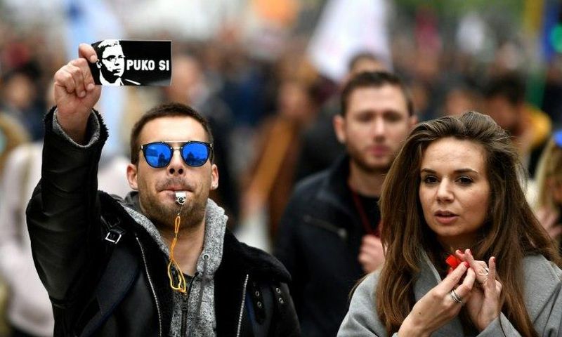 A protestor holds a sticker showing Aleksandar Vucic and reading: "You are finished"