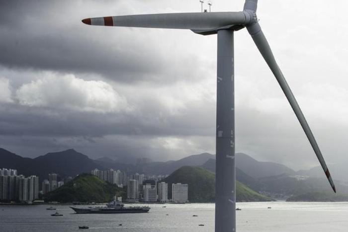 A Chinese aircraft carrier sails past a wind turbine as it sails into Hong Kong on July 7, 2017