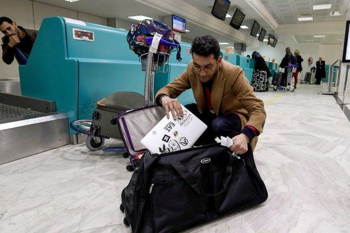 A Libyan traveller packs his laptop in his suitcase before boarding his flight for London at Tunis-Carthage International Airport on March 25, 2017