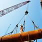 A worker stands on pipes at an offshore oil engineering company in Qingdao, in China's eastern Shandong province
