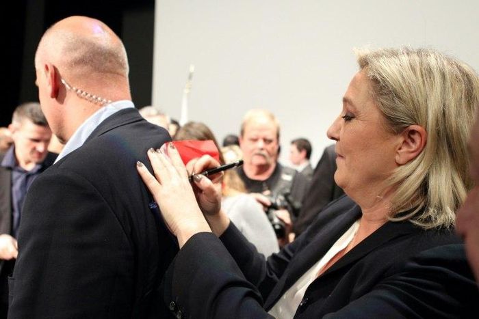 National Front (FN) leader Marine Le Pen (R) signs autographs on her bodyguard's back during a 2015 campaign rally in Corsica
