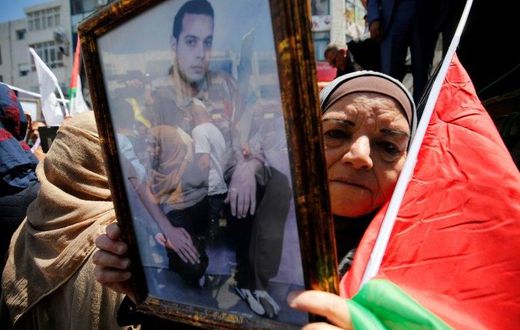 A woman holds the portrait of a Palestinian prisoner during a rally in the West Bank city of Ramallah to show support for hundreds in Israeli jails who went on hunger strike on April 17, 2017