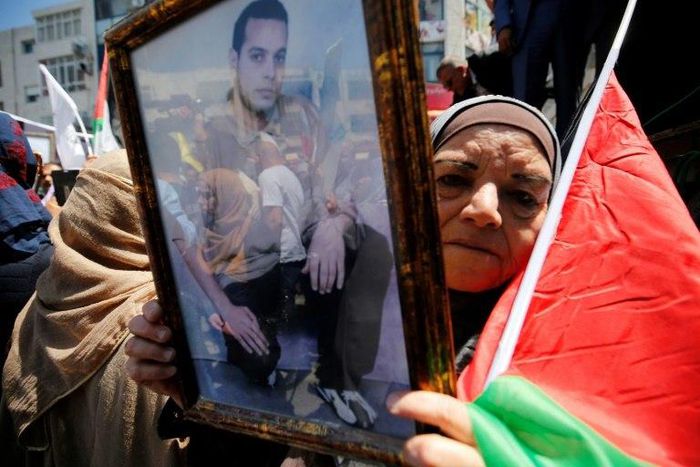 A woman holds the portrait of a Palestinian prisoner during a rally in the West Bank city of Ramallah to show support for hundreds in Israeli jails who went on hunger strike on April 17, 2017