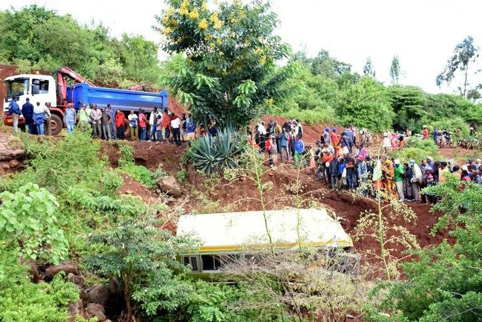 People look at the wreckage of a bus that plunged into a gorge while transporting children from Arusha to Karatu, on May 6, 2017