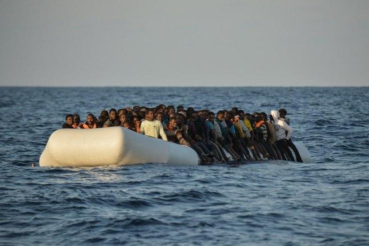 Migrants and refugees sit on a rubber boat off the Libyan coast in the Mediterranean Sea on November 3, 2016