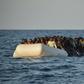 Migrants and refugees sit on a rubber boat off the Libyan coast in the Mediterranean Sea on November 3, 2016