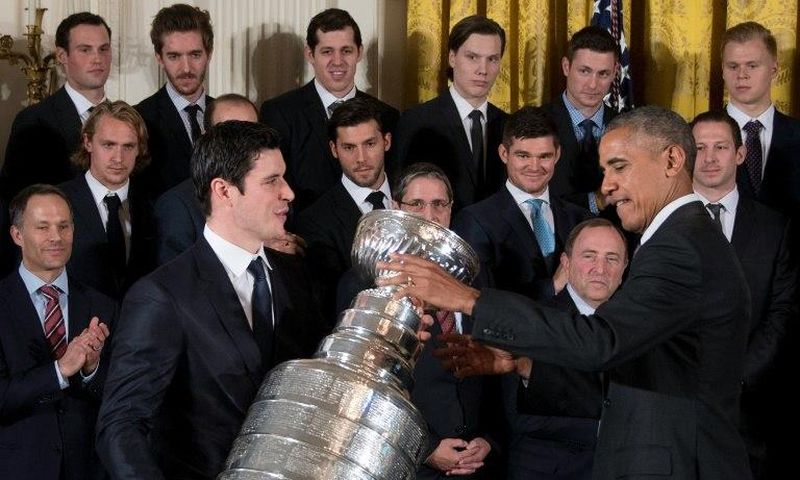 US President Barack Obama (R) gestures as Pittsburgh Penguins captain Sidney Crosby (L) picks up the Stanley Cup during an event at the White House in Washington, DC, October 6, 2016, honoring the Penguins 2016 Stanley Cup victory