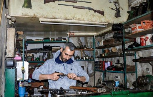 Syrian Abboud Jan repairs a disassembled rifle in his firearm-repair workshop in northeastern Syria's Hasakeh city
