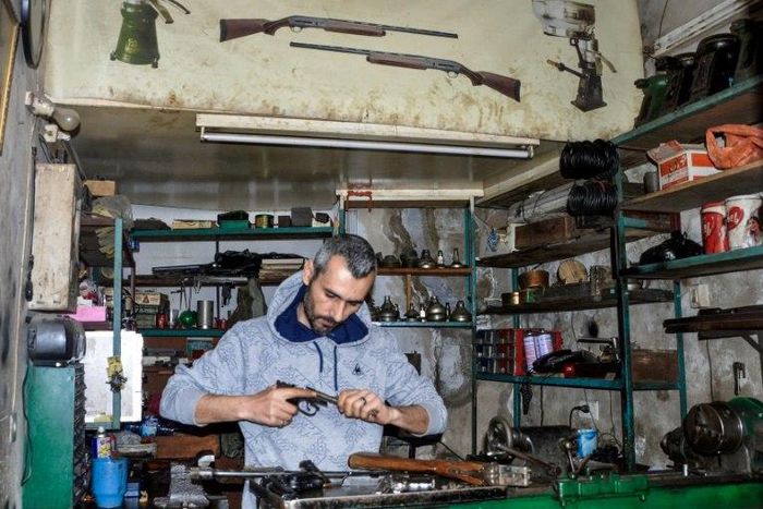 Syrian Abboud Jan repairs a disassembled rifle in his firearm-repair workshop in northeastern Syria's Hasakeh city