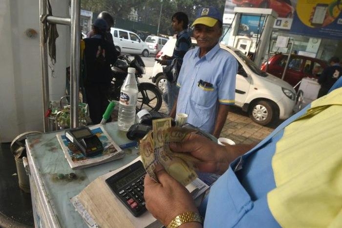 An Indian customer pays for fuel with old 500 rupee notes at a petrol station in New Delhi on the last day on which the old currency can be used to purchase fuel