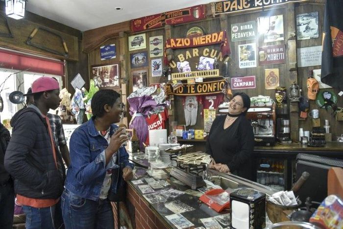 Migrants from Senegal and Niger joke with the waitress in the main bar of Sant' Alessio in Aspromonte, a small village of 330 inhabitants in Calabria, southern Italy
