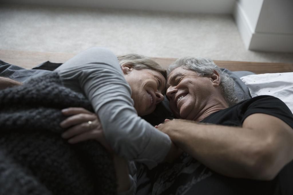 Affectionate, romantic senior couple cuddling in bed