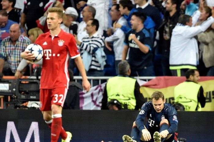 Bayern Munich goalkeeper Manuel Neuer (R) removes his boot during the Champions League quarter-final second leg against Real Madrid at the Santiago Bernabeu stadium in Madrid on April 18, 2017
