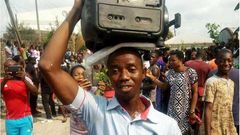 A man makes his protest by holding a generator set on his head.