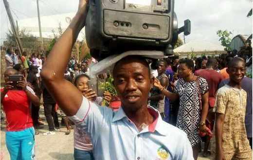 A man makes his protest by holding a generator set on his head.
