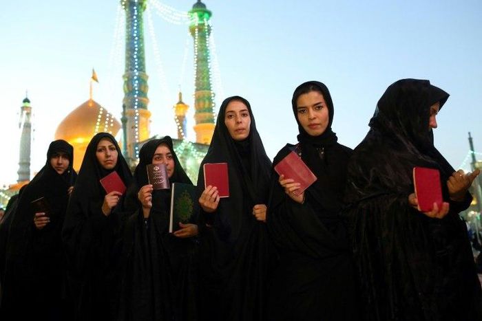 Iranian women hold their IDs as they wait to vote at the Massoumeh shrine in the holy city of Qom on May 19, 2017