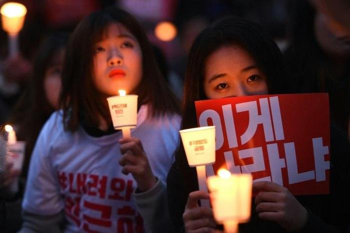 Protesters hold candles and banners calling for the resignation of South Korea's President Park Geun-Hye during a rally in Seoul on November 19, 2016