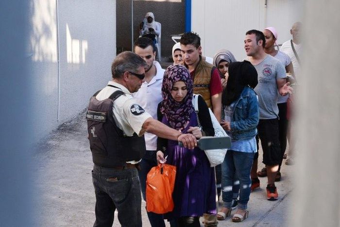 Refugees undergo security checks as they enter an asylum service in Athens for their hearing on August 22, 2016
