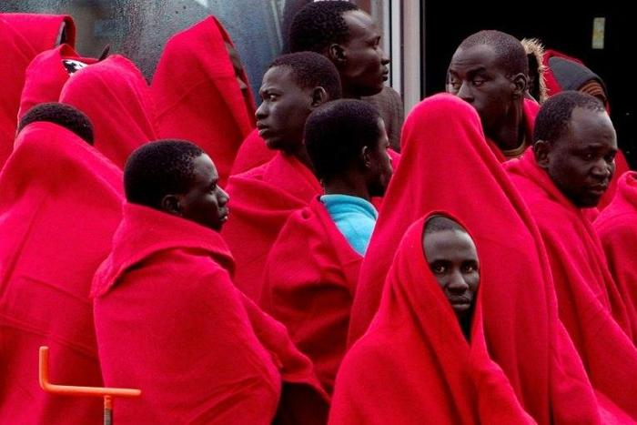 A group of migrants cover themselves with blankets following their arrival on board of a Spanish coast guard vessel into the southern Spanish port of Malaga on December 3, 2016